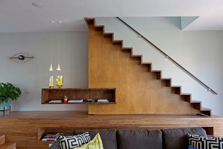 Modern living room with floating wooden staircase, dark sofa, and minimalist decor